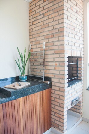 Een keuken met een bakstenen muur, een aanrecht, een plant en een grill.