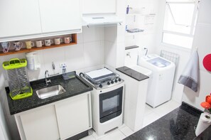 A compact kitchen with a sink, stove, and washing machine.