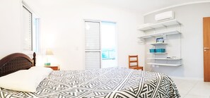 Une chambre à coucher comprenant un lit, une chaise, une table de chevet, une lampe, une armoire et des étagères intégrées.