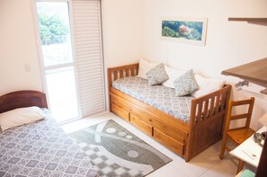 Un dormitorio pequeño y acogedor con una cama individual, cabecera de madera, una mesita y una silla.