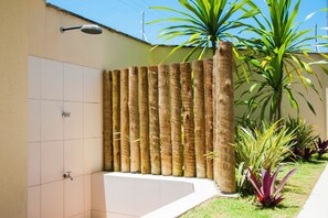 A tiled wall with a bamboo fence, a metal light fixture, and a small garden with plants.