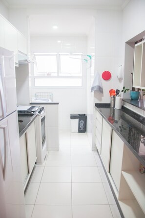 A kitchen with white cabinets, a stove, a sink, and a window.