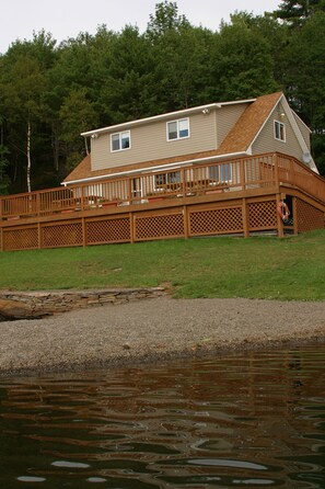 A house with a deck, a lifebuoy, and a pond in the foreground. - Exclusive Lakehouse  (Jefferson)