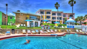 A hotel with a swimming pool, lounge chairs, and palm trees. - Spacious 3 Bedrm/2 Bth OceanFront Apt w/Large Balcony Overlooking Pool. Sleeps 9 (Daytona Beach Shores)