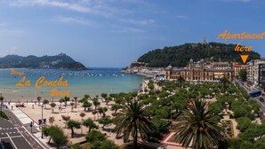 Un paisaje costero con playa, palmeras y edificios históricos.