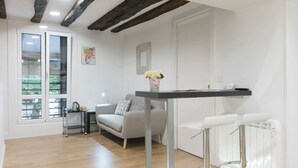 Una sala de estar moderna con un sofá gris, una mesita, un radiador y una ventana con persianas.
