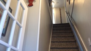 A carpeted staircase with a handrail, white walls, and a decorative lobster wall art piece. - Cozy Beach Apartment, private entrance and parking spot . <br> (Middletown)