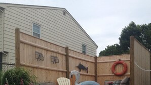 A wooden fence with a life preserver and a fish decoration. - Cozy Beach Apartment, private entrance and parking spot . <br> (Middletown)