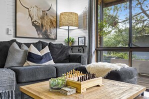 A modern living room with a grey sofa, a chessboard, and a lamp.