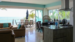 A spacious living area with a kitchen island, seating, and large windows overlooking the ocean. - Paradise Perfected! Your Exclusive Beachfront Escape in Bucerías. (Bucerias)