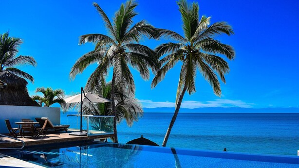 A poolside area with lounge chairs and a view of the ocean. - Paradise Perfected! Your Exclusive Beachfront Escape in Bucerías. (Bucerias)
