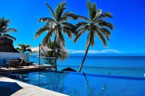 Un espace aménagé au bord de la piscine, avec des chaises longues et une vue sur l’océan.