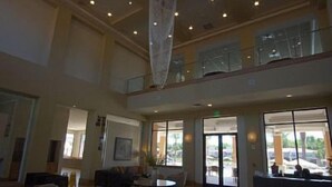 A spacious lobby with a high ceiling, large windows, and a seating area with sofas and a coffee table. - 3 BR/3BH, 3 miles to Disney, Gates Resort, Pool with Water Slides (Kissimmee)