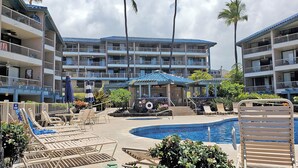 Et hotel med flere balkoner, en swimmingpool og liggestole.