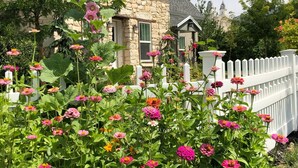 A stone house with a white picket fence, surrounded by vibrant flowers. - Manti Cottage, Historic Pioneer Home (Manti)