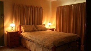A bedroom with a bed, two bedside tables, and curtains.