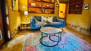 Ein gemütliches Wohnzimmer mit einem blauen Sofa, einem runden Couchtisch und einem gemusterten Teppich.