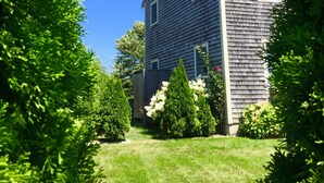 A two-story house with a dark siding exterior, surrounded by lush green trees and a well-maintained lawn.