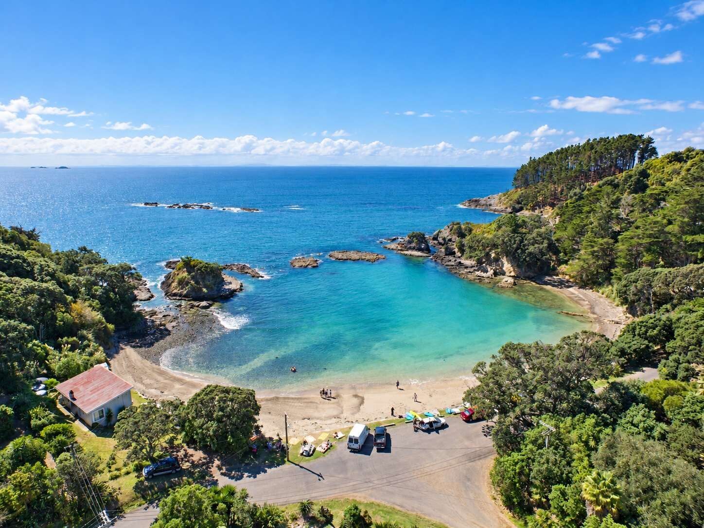 A coastal property with a beach, a parking area, and a small building.