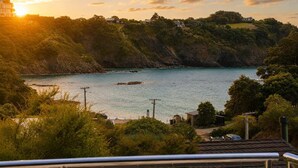 A coastal landscape with a view of the sea, hills, and a building in the distance. - The Palms - Sea Views near Sandy Bay (Sandy Bay (Waiheke))