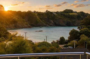 Un paysage côtier offrant une vue sur la mer, des collines et un bâtiment situé au loin.