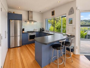 A modern kitchen with a large island, stainless steel appliances, and a view of greenery.
