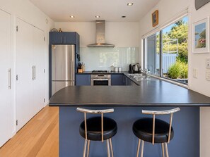 Une cuisine moderne dotée d’un îlot central, d’appareils électroménagers en acier inoxydable et d’une fenêtre offrant une vue sur l’extérieur.