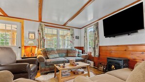 A cozy living room with a sofa, armchair, and a fireplace. - Rangeley Manor 2 | Great Cabin with Shared Access to Rangeley Lake. (Rangeley)