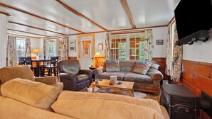 A cozy living room with a sofa, armchairs, a coffee table, and a fireplace. - Rangeley Manor 2 | Great Cabin with Shared Access to Rangeley Lake. (Rangeley)