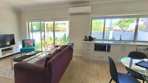 A modern living room with a TV, sofa, and dining area. - Central Sojourn on Wilcox Unit 1 - Central two bedroom apartment with a queen and double bed (Albury)