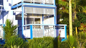 Un edificio de varios pisos con balcones, rodeado de vegetación tropical.