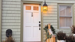 A house with a white front door, a mailbox, and a wooden porch with a lantern. - Magical Little Home in Historic District • Parking  • Rustic Luxury  • Outdoor.. (Marblehead)