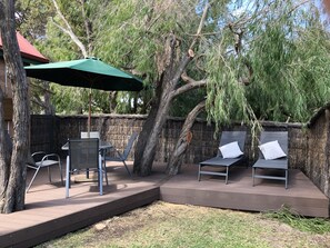 Relax in a serene outdoor space with a seating area, umbrella, and tree views.