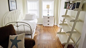 Une chambre à coucher avec un lit, une table de chevet, une lampe et une bibliothèque.