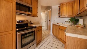 A kitchen with wooden cabinets, a microwave, an oven, and a tiled floor.