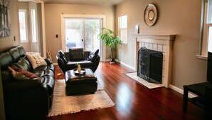 A living room with a fireplace, leather sofas, and a large window.