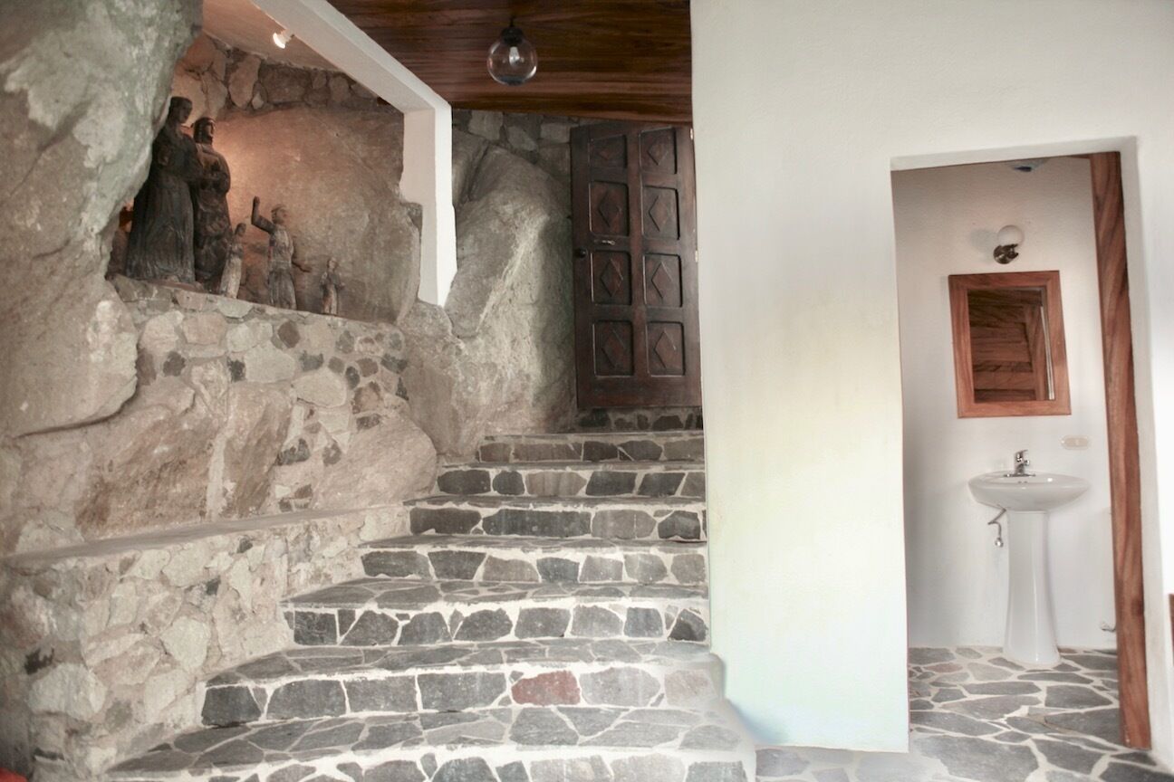 Una escalera de piedra que lleva a una habitación con una puerta de madera y un lavamanos blanco.