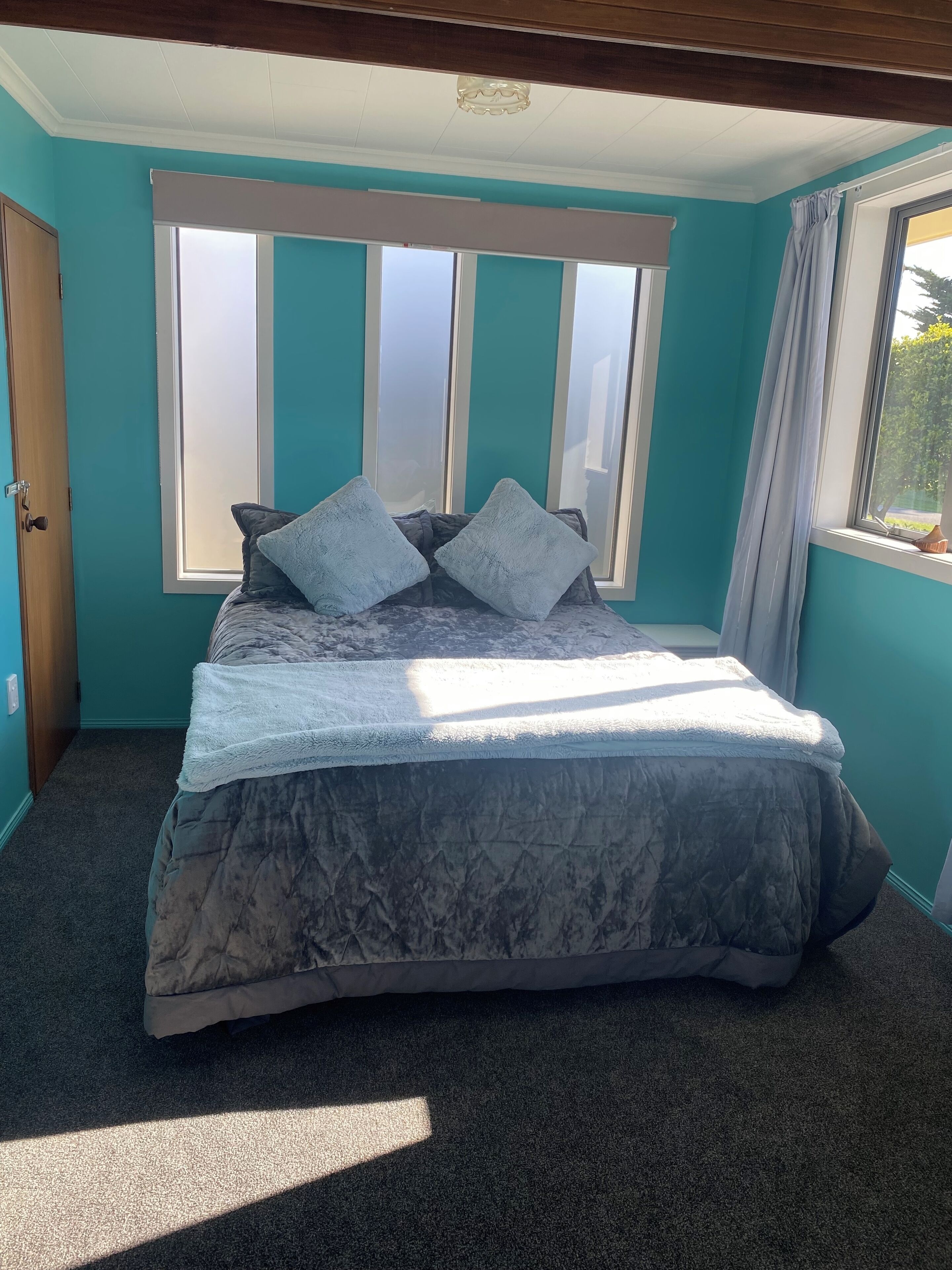 A bedroom with a bed, a window, and a door.