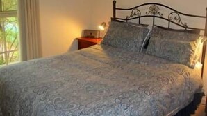 Una camera da letto con un letto, un comodino e una finestra con tende.