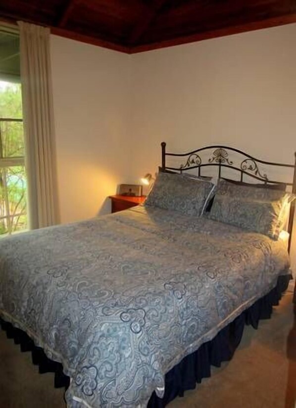 A bedroom with a bed, a nightstand, and a window with curtains.