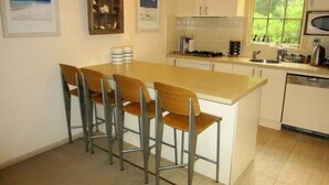 Una cucina con isola centrale, sgabelli da bar, forno a microonde e una finestra vista verde.