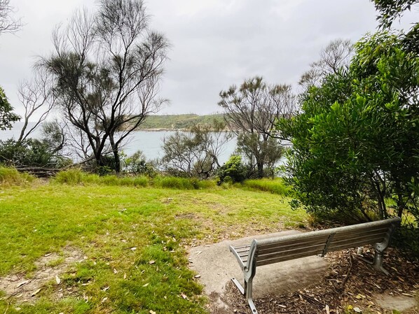 A bench in a park with a view of a lake and trees.