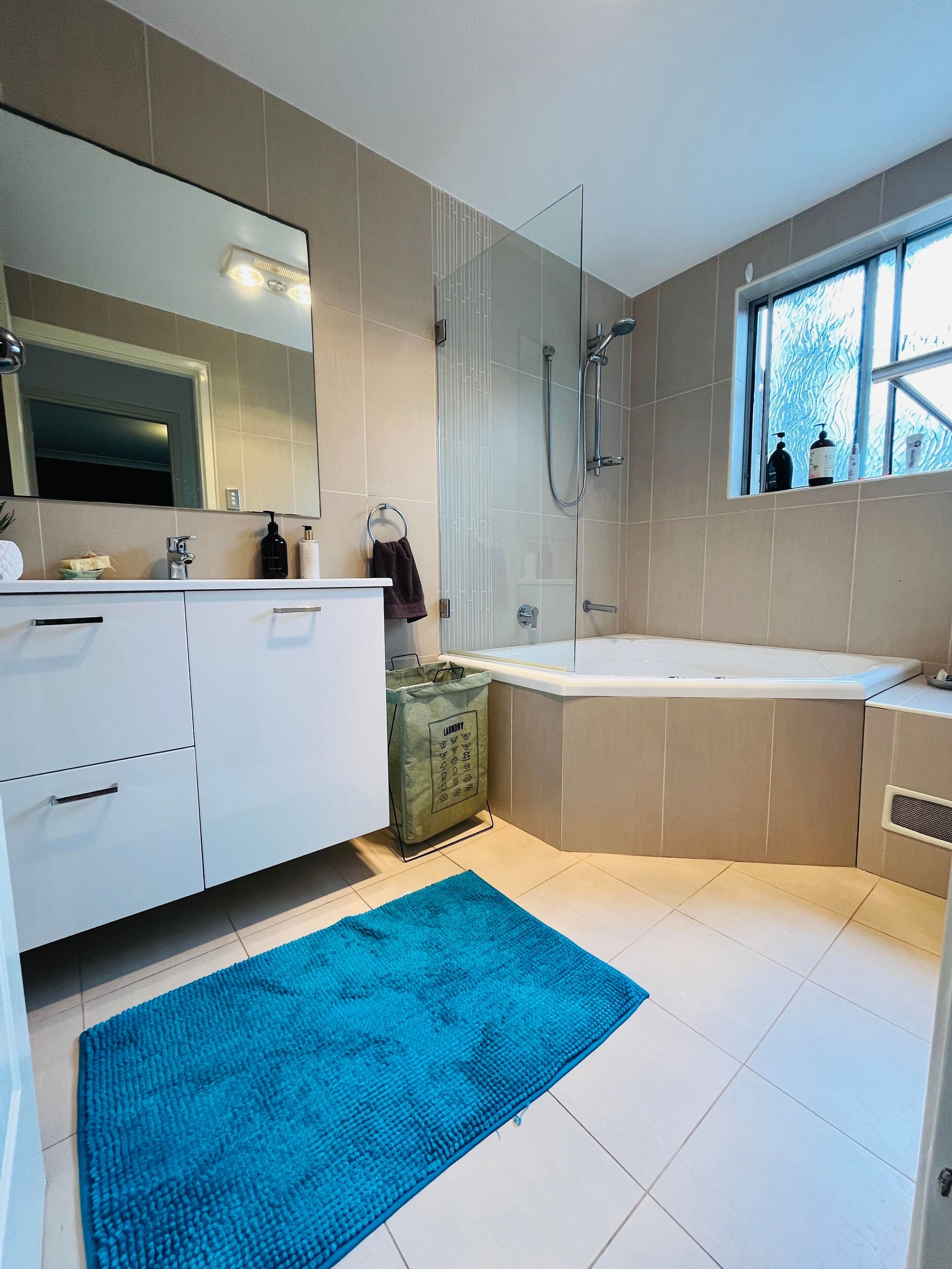 A modern bathroom with a large mirror, a bathtub, and a shower.