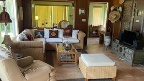 A cozy living room with a sofa, armchair, and ottoman, a television, and wicker furniture. - Sebring Lakefront Home - Lake Josephine 'Little Piece Of Heaven' (Sebring)