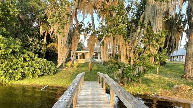 A wooden bridge leading to a building surrounded by trees with hanging moss. - Sebring Lakefront Home - Lake Josephine 'Little Piece Of Heaven' (Sebring)