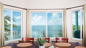 Enjoy a meal with a view of the ocean from this dining area, featuring a large table for four and expansive glass doors.
