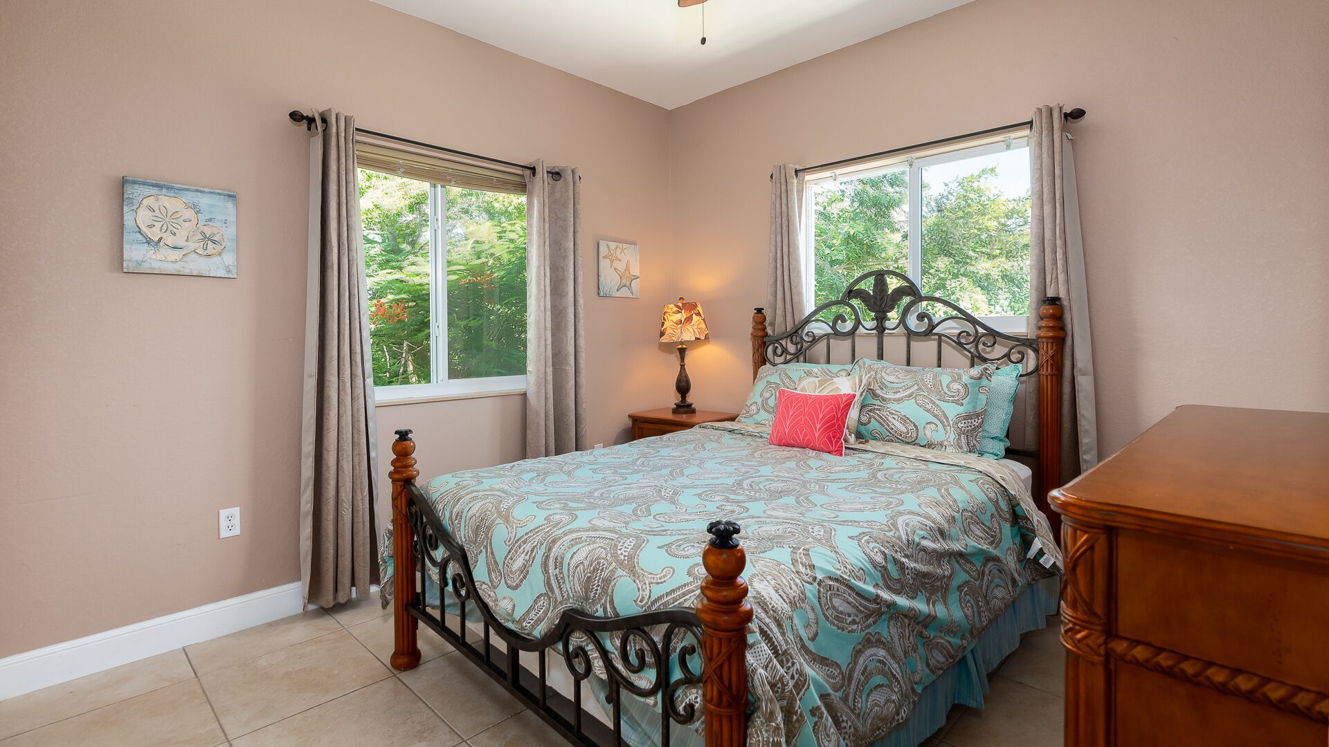 A bedroom with a bed, two windows, a nightstand, a lamp, and a dresser.
