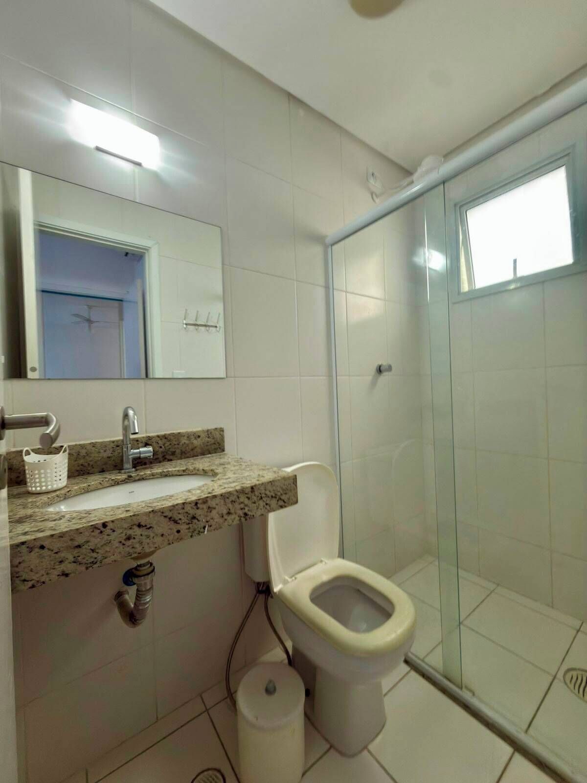 A bathroom with a shower, toilet, sink, and mirror.