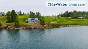 A Tide-Water Cottage & Loft with a view of a calm lake, surrounded by lush greenery and a few houses. - Sitting on the edge of Cobscook Bay at Rossport by the Sea (Bali)