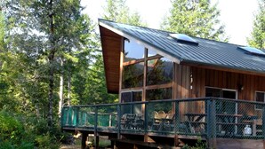 A rustic cabin with a wooden exterior, large windows, and a covered deck area.